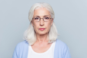 Close up portrait of serious, aged, charming woman in glasses over grey background