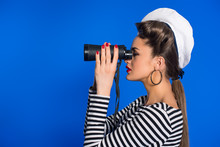 Side View Of Attractive Young Woman In Retro Clothing With Binoculars Isolated On Blue