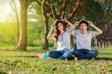 Wall Mural - couple holding a book and resting in park