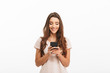 © Drobot Dean - Cheerful brunette woman in t-shirt writing message on smartphone