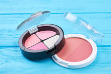 Pink Eyeshadows And Blusher Close Up. Decorative Cosmetic Products On Blue Wooden Background. Female Beauty Essentials.