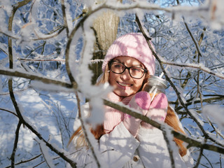 Wall Mural - Adorable happy young blonde woman in pink knitted hat scarf having fun drinking hot tea from mug snowy winter park forest in nature