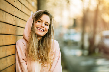 Wall Mural - cool young woman in pink hoodie on wooden background