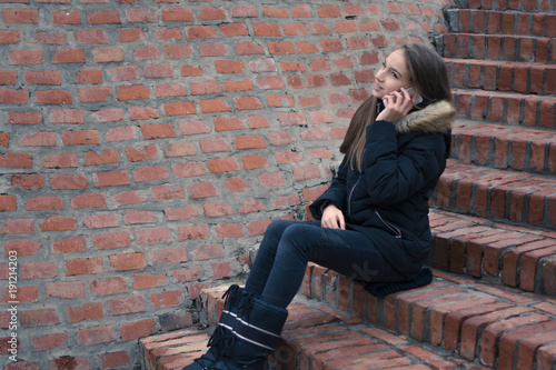 Fotografie, Obraz Teenage girl talking on the smartphone outside