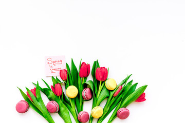  Spring gift. Flowers and sweets. Tulips and sweets macarons on white background top view copy space
