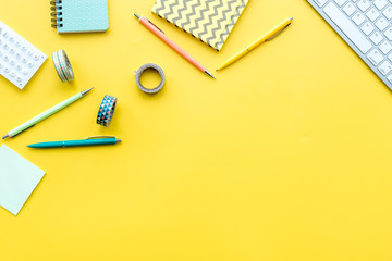 Wall Mural - Scattered stationery on student's desk. Yellow background top view copy space