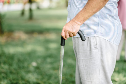 cropped shot of an elderly senior man holding onto a cane in the park