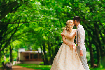 Wall Mural - guy hugging his girlfriend during dancing in the green park and she laughs