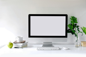Mockup desktop Blank screen modern computer, coffee mug, house plant, books and office supplies.