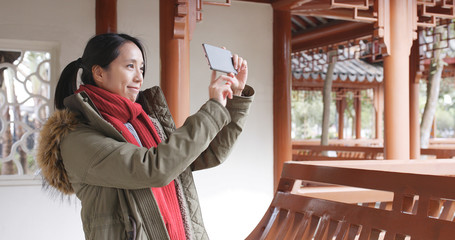 Wall Mural - Asian woman visit chinese garden and using cellphone to taking photo and video