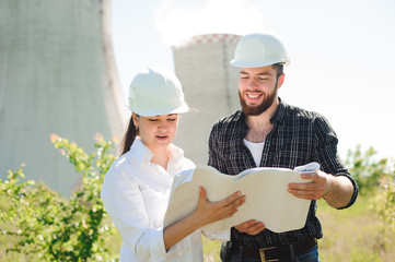 two engineers standing at electricity station, discussing plan