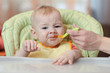 © Oksana Kuzmina - Cute baby boy refusing to eat food from spoon with face dirty of vegetable puree.
