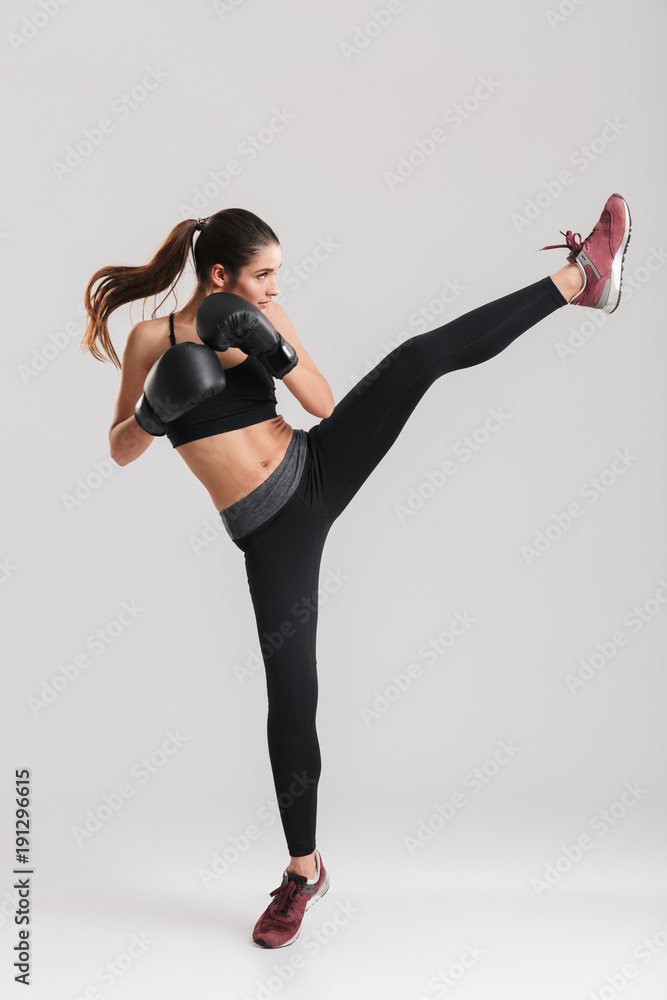 фотографія Photo in profile of focused brunette woman doing kickboxing exercises in boxing