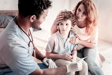 Wall Mural - Serious disease. Worried mature lady hugging her son tightly while listening to a medical worker and hearing the diagnosis.