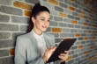 © Nebojsa - Close-up of an attractive young girl using tablet isolated on brick wall.