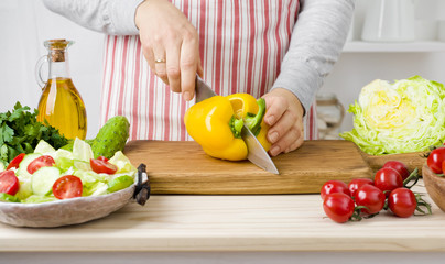 Woman hands cutting vegetables on board in kitchen cooking salad