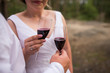 The bride and groom holding glasses with red wine. Wedding glasses