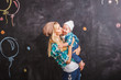 © Юлия Буракова - A modern mom hipster is holding a child's kiss and hugs him on a black background. Young beautiful happy mother with little son in her arms who is smiling. Space for text. Mother's day.