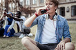 © Viacheslav Yakobchuk - So thirsty. Nice positive young man sitting on the grass and drinking coke while being thirsty