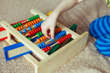 Preschooler baby learns to count. Cute child playing with abacus toy. Little boy having fun indoors at home, kindergarten or day care centre. Educational concept for preschool kids.