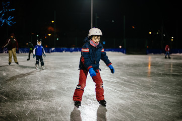 10 year old childl skates on the ice in the evening on an illuminated track