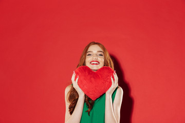 Poster - Redhead young happy lady holding plush heart in hands.