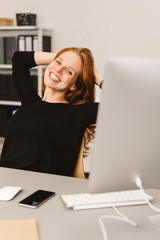 Wall Mural - Happy woman sitting at desk in a modern office