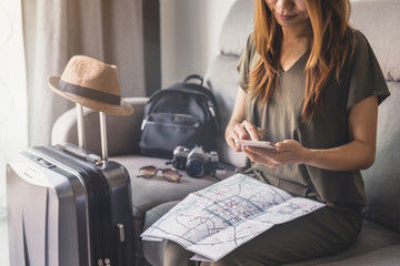 Young woman traveler using smart phone and looking map