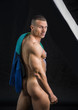 © theartofphoto - Portrait of naked handsome young man with languishing look covering crotch with a towel, against black background