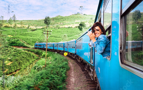 Fotomural Happy smiling woman looks out from window traveling by train on most picturesque