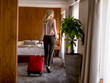 © BGStock72 - Young businesswoman arrives in a hotel room with red suitcase