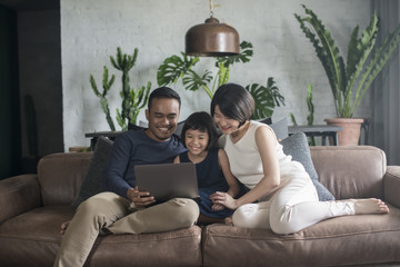 Happy Asian family using the computer together at home.