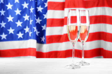 Wall Mural - Glasses of champagne on table against flag of the USA