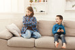© Prostock-studio - Two kids with remote control on couch at home