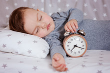 Baby Sleeping In A Crib With An Alarm Clock