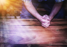 A Man Hands Pray Over Wooden Table With Bokeh Light Effected, Copy Space