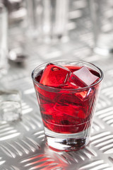 Red alcoholic cocktail with ice and cherry juice on iron table