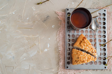 Piece of Fruit cake with strawberry, kiwi, peach, apple, custard cream and cup of tea on background holly branch with berry, fir cone, flower cinnamon stick