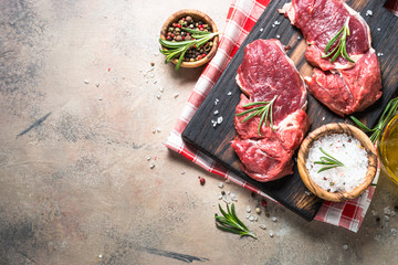 Raw beef steak with herbs on stone table. Top view.