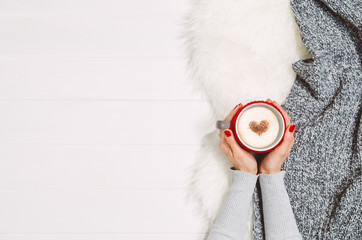 Woman hands holding coffee mug or cup on white wooden table. Photograph taken from above, top view with copy space