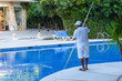A man, personnel cleaning the pool at a tropical resort.
