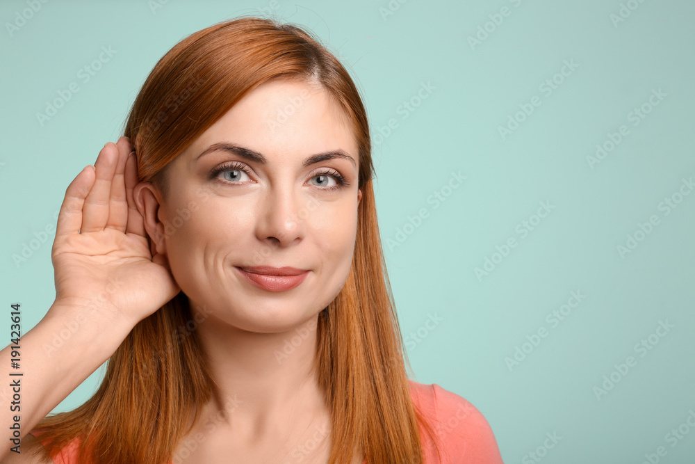 Young woman with hearing problem on color background