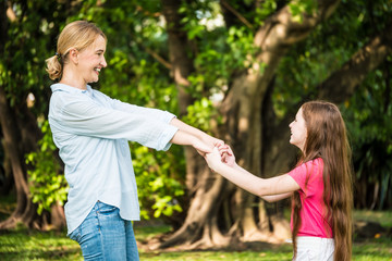 Wall Mural - Mother and daughter having fun together in a park. Family and lifestyle concept