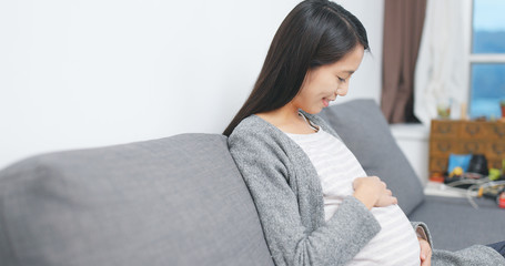 Poster - Pregnant woman looking at her tummy at home