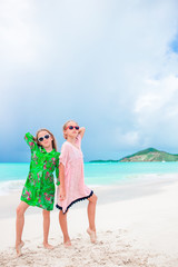 Little happy funny girls have a lot of fun at tropical beach playing together. Sunny day with rain in the sea