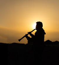 An Unidentified Man Plays Clarinet At Sunset
