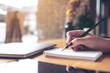 © Farknot Architect - Closeup image of woman's hand writing on a blank notebook with laptop , tablet and coffee cup on wooden table background