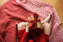 Overhead View Of A Girl Sitting Cross-legged Holding A Wrapped Christmas Gift