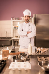 Wall Mural - young confectioner with arms crossed standing at counter in restaurant kitchen