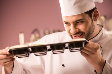 Wall Mural - confectioner checking dough in baking forms in restaurant kitchen